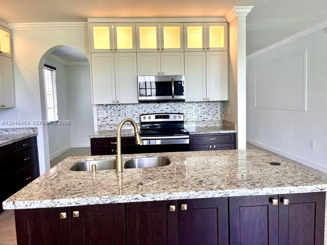 A kitchen features a granite island, dark lower cabinets, and white upper cabinets with lighting — 27448 SW 143rd Ct, Homestead FL 33032, HOMESTEAD, FL