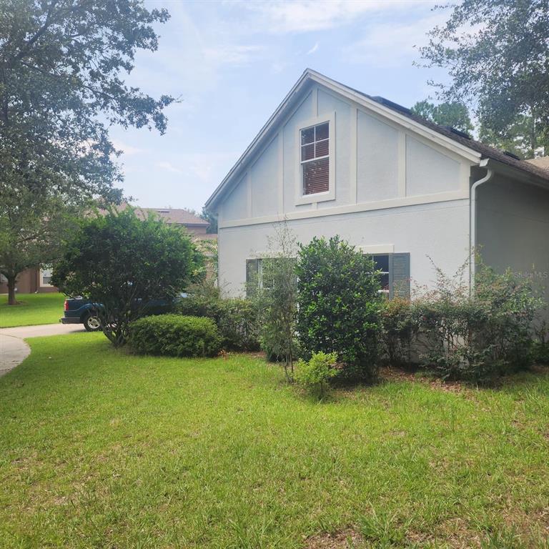 A light-colored house exterior features a gabled roof, a single upper window, and landscaping — 523 RIDGEWAY BOULEVARD, DELAND, FL