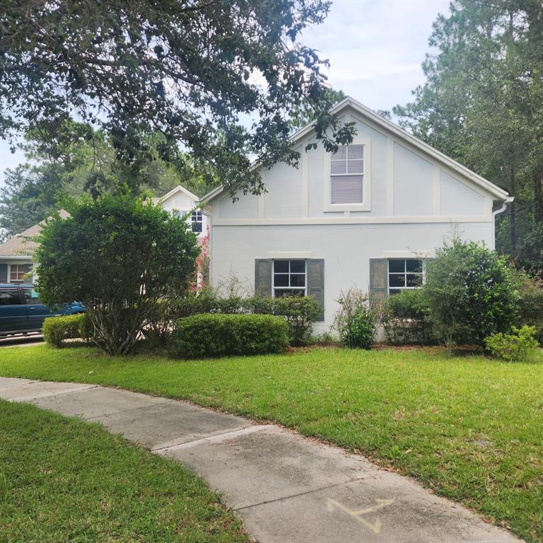 A light blue two-story house with white trim and dark shutters sits behind a lawn — 523 RIDGEWAY BOULEVARD, DELAND, FL