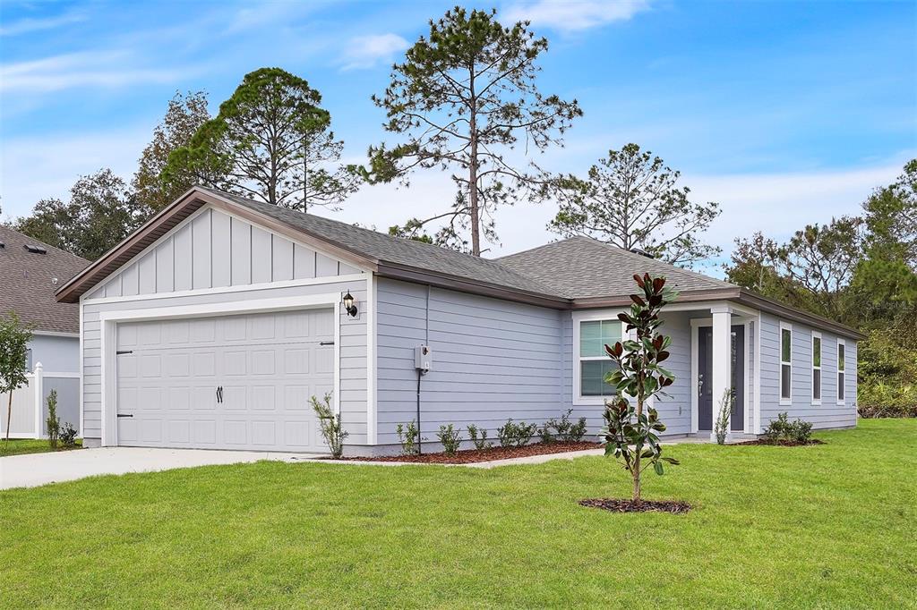 A light blue single-story house with a two-car garage and a front yard — 560 MARION OAKS MANOR, OCALA, FL