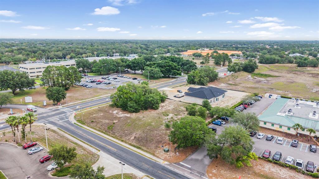 An aerial view shows a vacant lot situated between commercial buildings and parking lots — 00 QUALITY DRIVE, SPRING HILL, FL