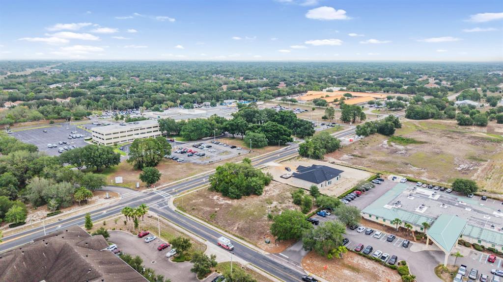 An aerial view shows commercial buildings, parking lots, and roads surrounded by trees and land — 00 QUALITY DRIVE, SPRING HILL, FL