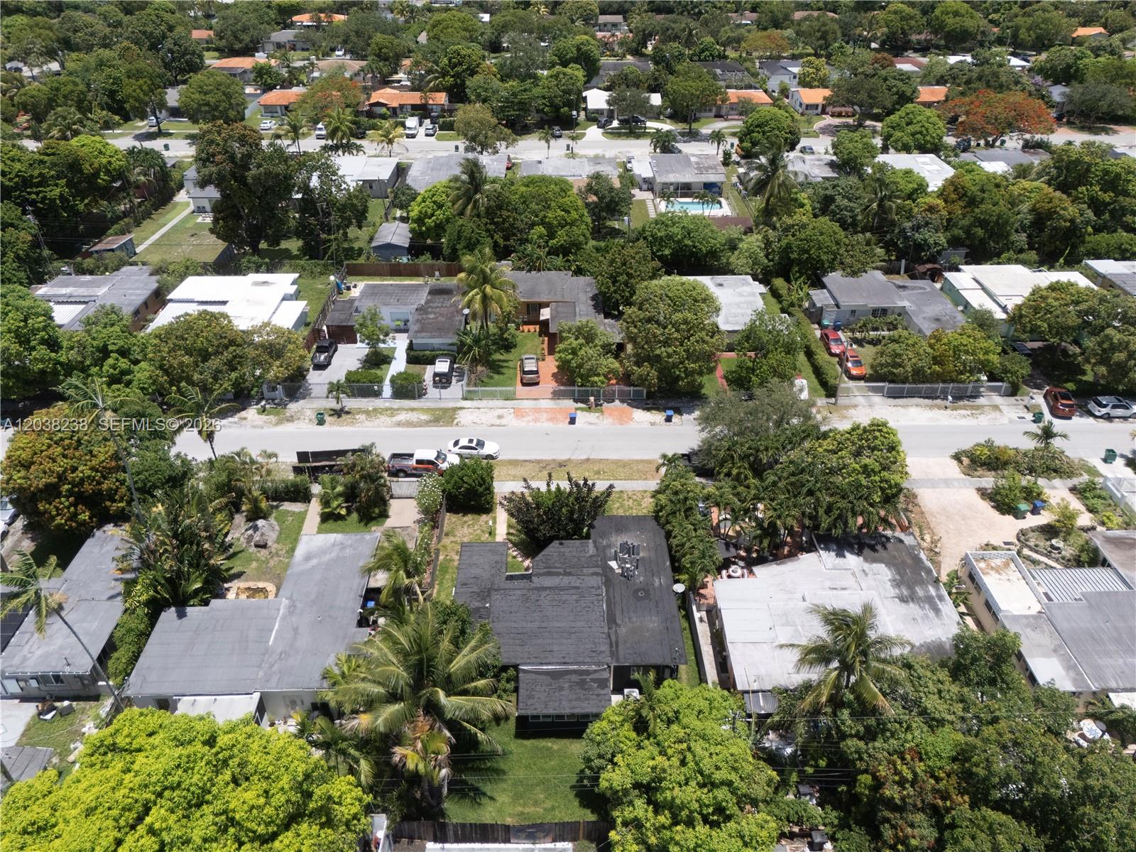 An aerial view shows a residential neighborhood with houses, lush trees, and parked cars — 334 NW 110th St, Miami FL 33168, MIAMI, FL