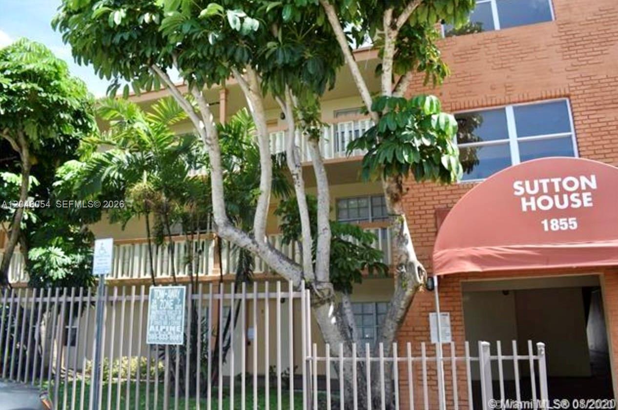 The exterior of a brick apartment building features a red awning and a metal fence — 1855 NE 121st St # 16, North Miami FL 33181, NORTH MIAMI, FL