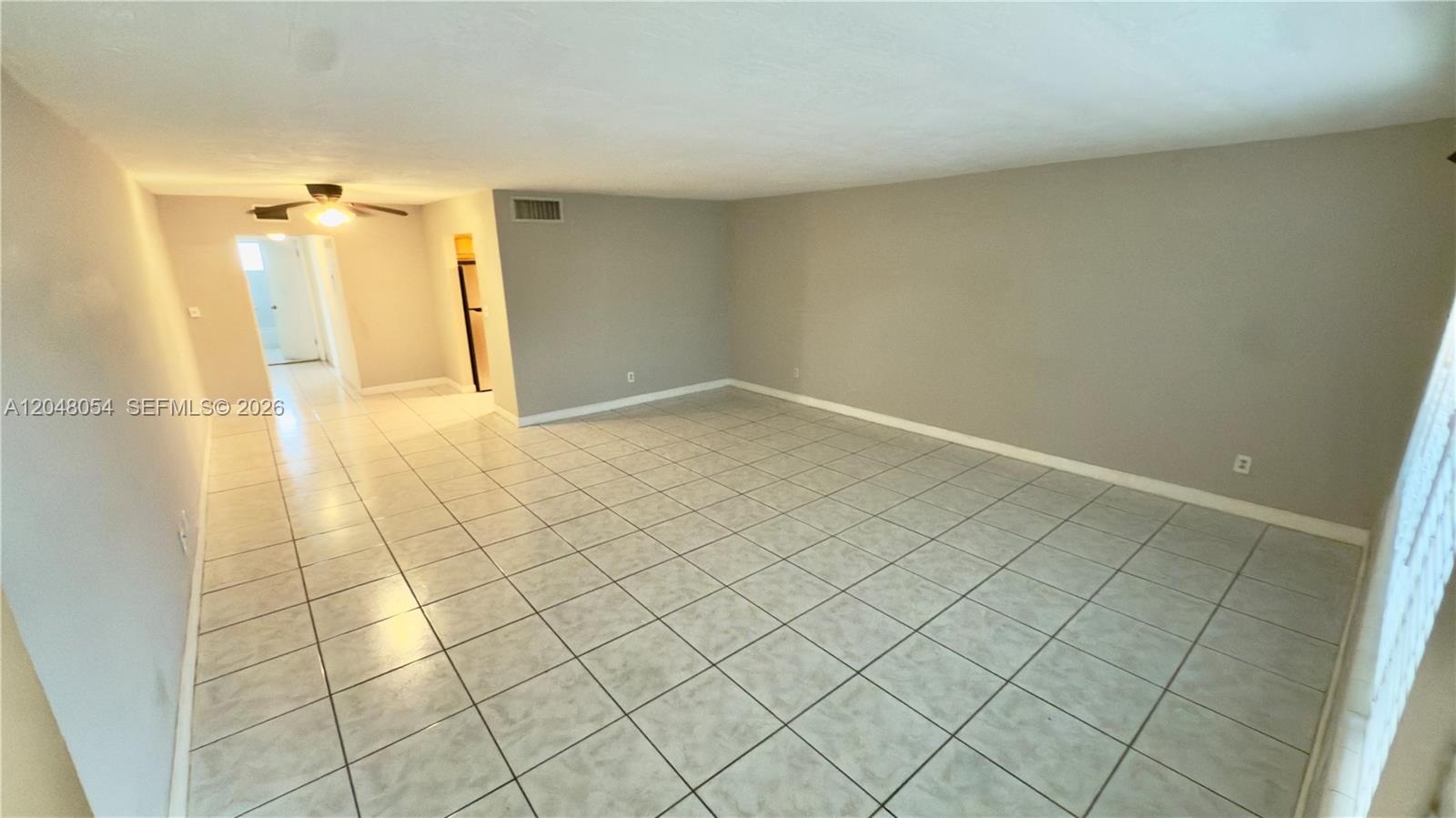 An empty living room features light-colored tile flooring, gray walls, and a ceiling fan — 1855 NE 121st St # 16, North Miami FL 33181, NORTH MIAMI, FL