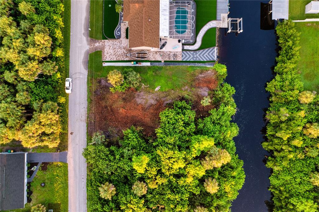 An aerial view shows a vacant lot situated between a residential house and a canal — 18522 AYRSHIRE CIRCLE, PORT CHARLOTTE, FL