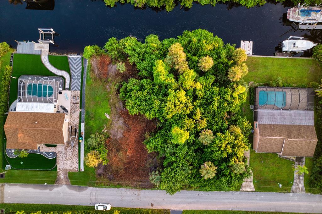 An aerial view shows a vacant lot situated between two houses with pools and boat docks — 18522 AYRSHIRE CIRCLE, PORT CHARLOTTE, FL