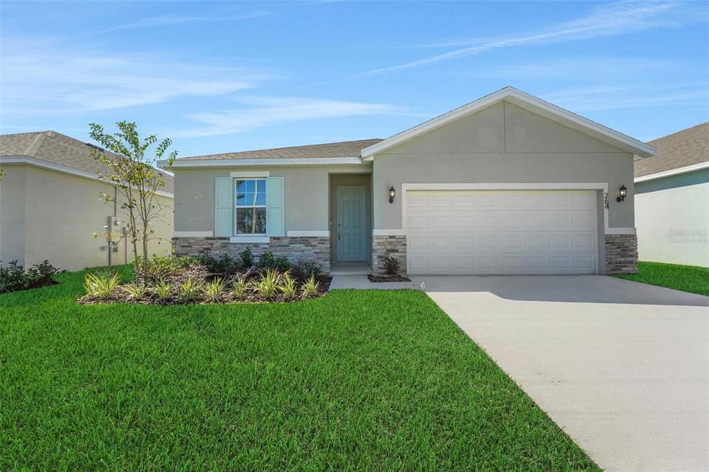 A single-story suburban house with a light gray exterior, stone accents, and a two-car garage — 1040 LUKE AVENUE, WINTER HAVEN, FL