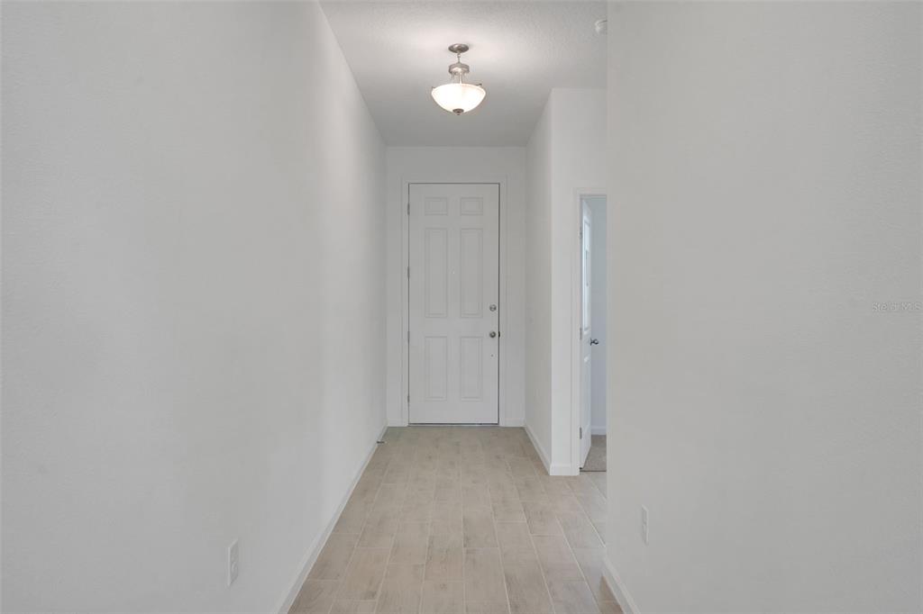 A bright entryway features white walls, light-colored tile flooring, and a central ceiling light — 1040 LUKE AVENUE, WINTER HAVEN, FL