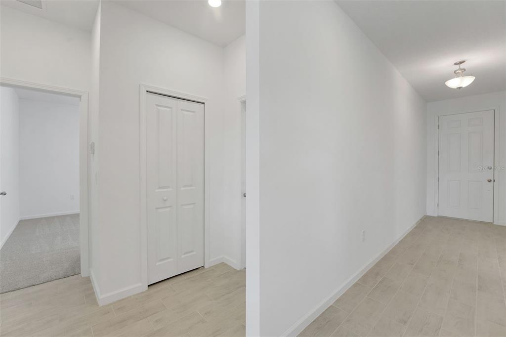A bright entryway features white walls, light tile flooring, a closet, and a front door — 1040 LUKE AVENUE, WINTER HAVEN, FL