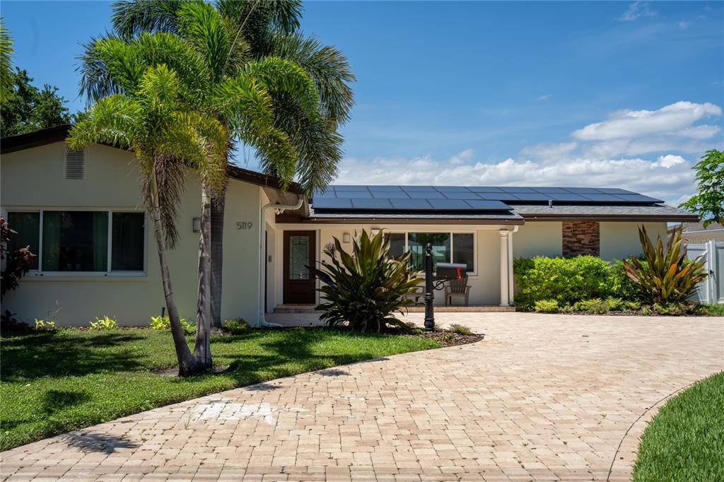 A single-story house with a paved driveway, solar panels on the roof, and palm trees — 5119 VENETIAN BOULEVARD NE, ST PETERSBURG, FL
