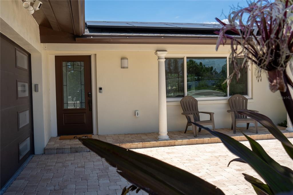 A paved patio leads to a front door and a window with two chairs — 5119 VENETIAN BOULEVARD NE, ST PETERSBURG, FL