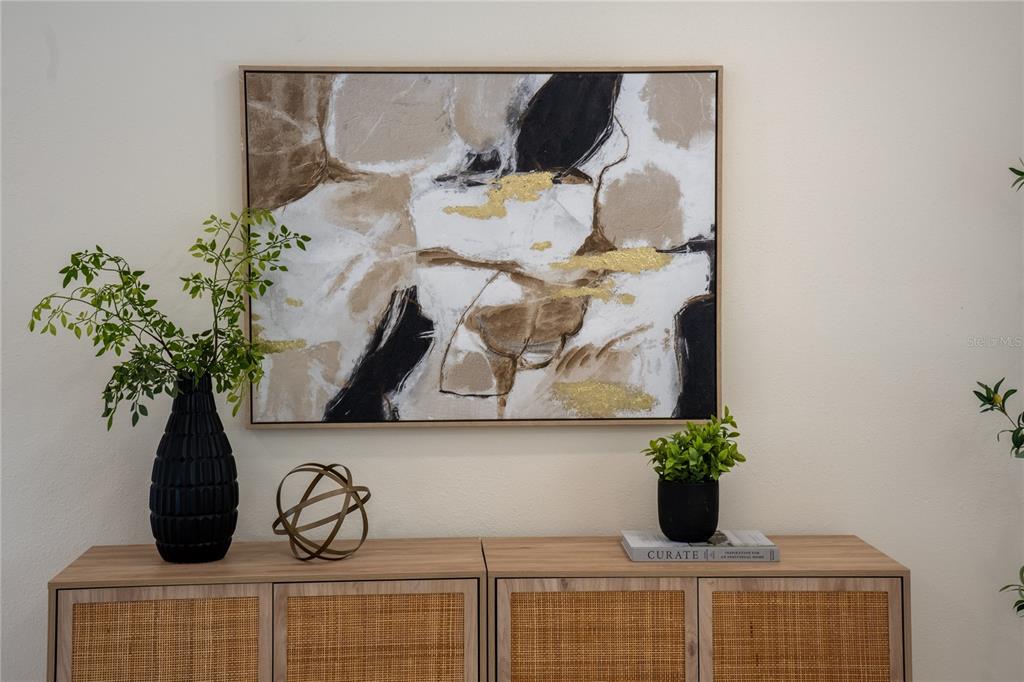 A piece of abstract art hangs above a wooden sideboard decorated with plants and decor — 5119 VENETIAN BOULEVARD NE, ST PETERSBURG, FL