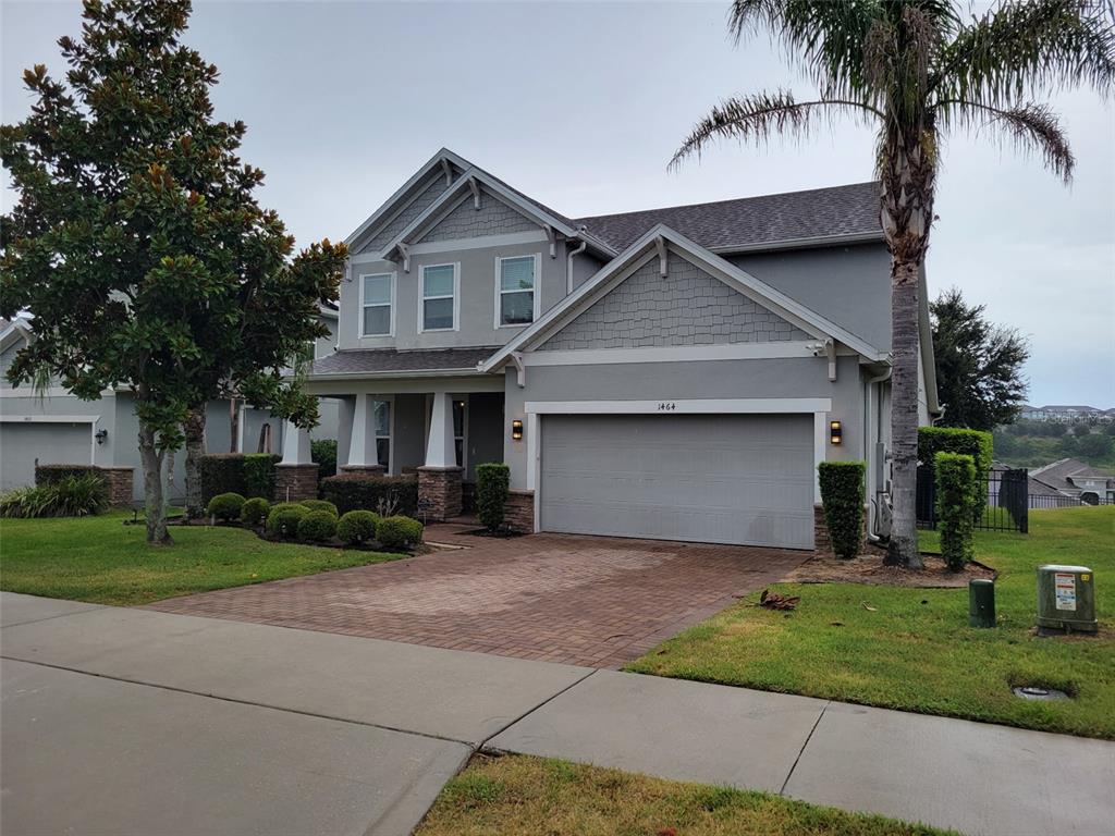 A two-story suburban house with a gray exterior, shingled roof, and a paved driveway — 1464 CABOT DRIVE, CLERMONT, FL