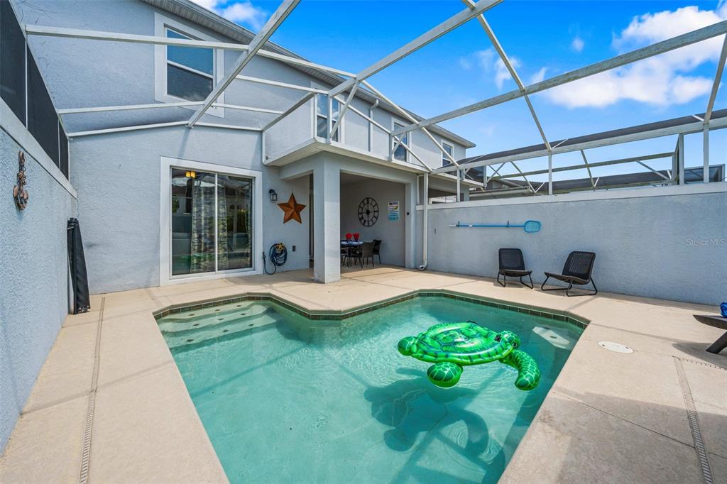 A screened-in patio features a swimming pool with a turtle float and outdoor seating — 218 OCEAN COURSE AVENUE, DAVENPORT, FL
