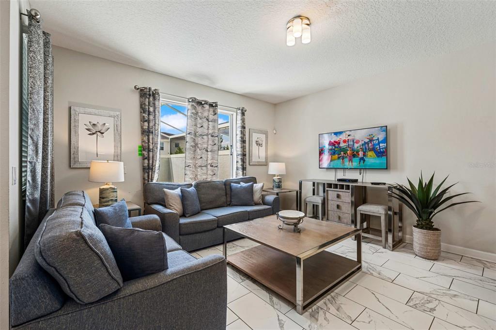 A living room features gray sofas, a square coffee table, and white tile flooring — 218 OCEAN COURSE AVENUE, DAVENPORT, FL