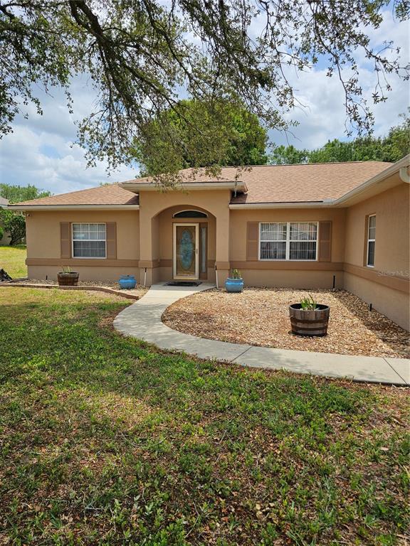 The exterior of a tan, single-story house features a front walkway and a gravel yard — 5280 SW 88TH PLACE, OCALA, FL