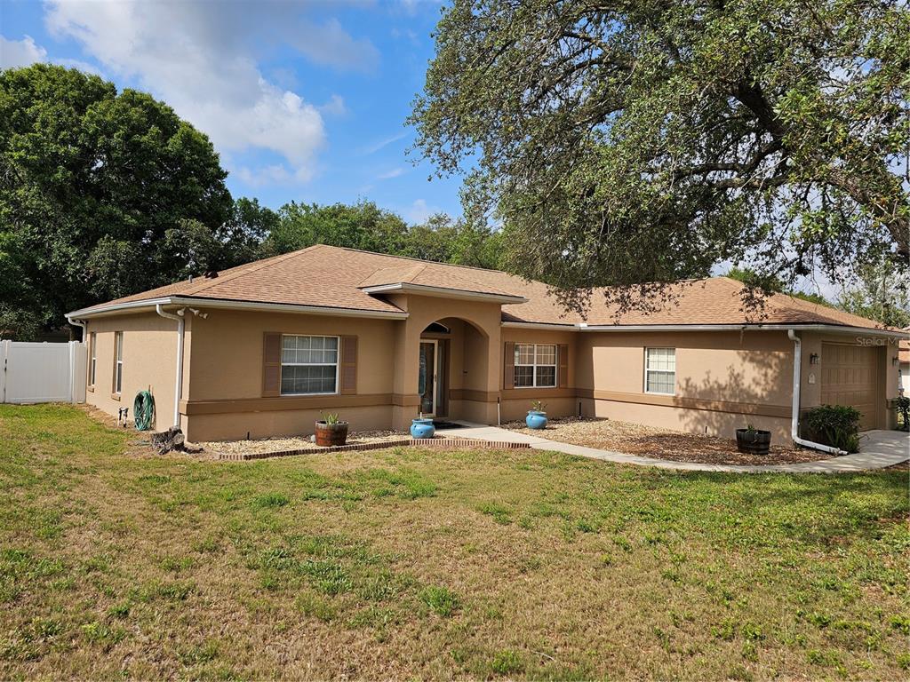 A single-story tan stucco house with a brown shingled roof and a front yard — 5280 SW 88TH PLACE, OCALA, FL