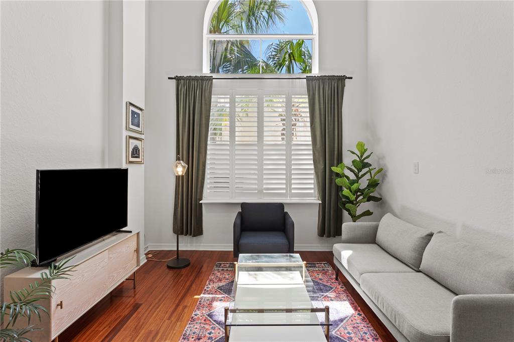 A living room features a high arched window, hardwood floors, a sofa, and a television — 700 S HARBOUR ISLAND BOULEVARD UNIT 109, TAMPA, FL