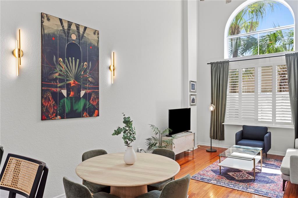A dining and living area with high ceilings, hardwood floors, and a large arched window — 700 S HARBOUR ISLAND BOULEVARD UNIT 109, TAMPA, FL