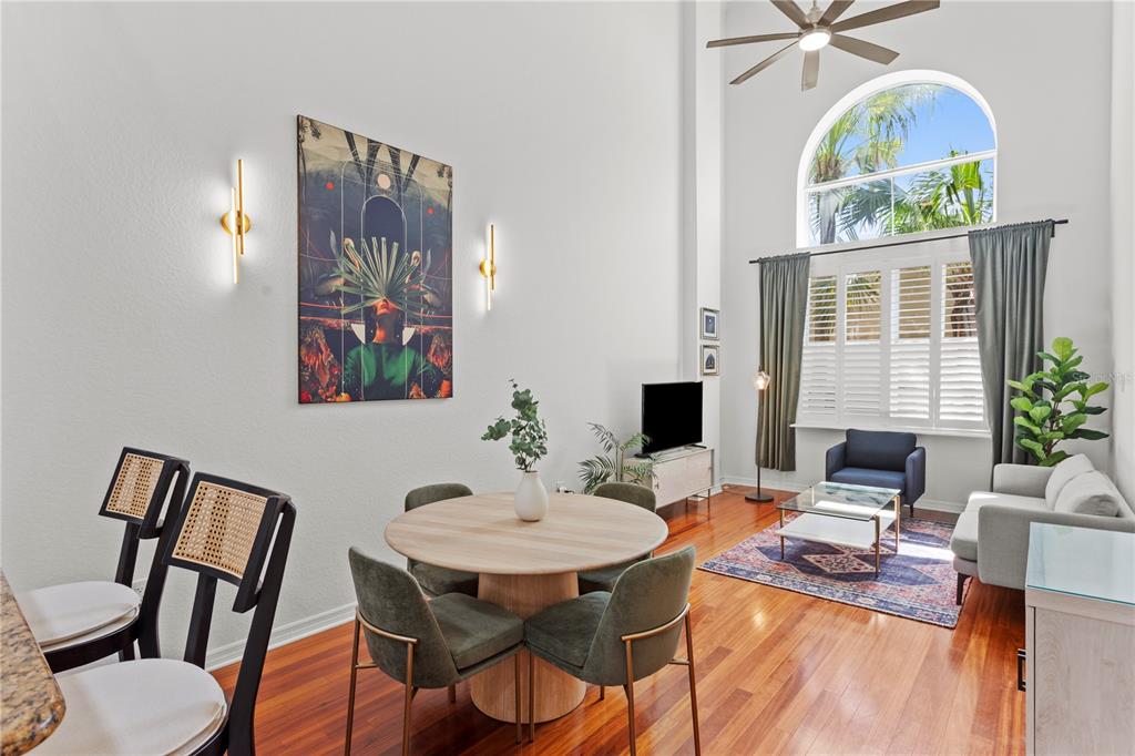 A high-ceilinged living and dining area features hardwood floors, a round table, and arched windows — 700 S HARBOUR ISLAND BOULEVARD UNIT 109, TAMPA, FL