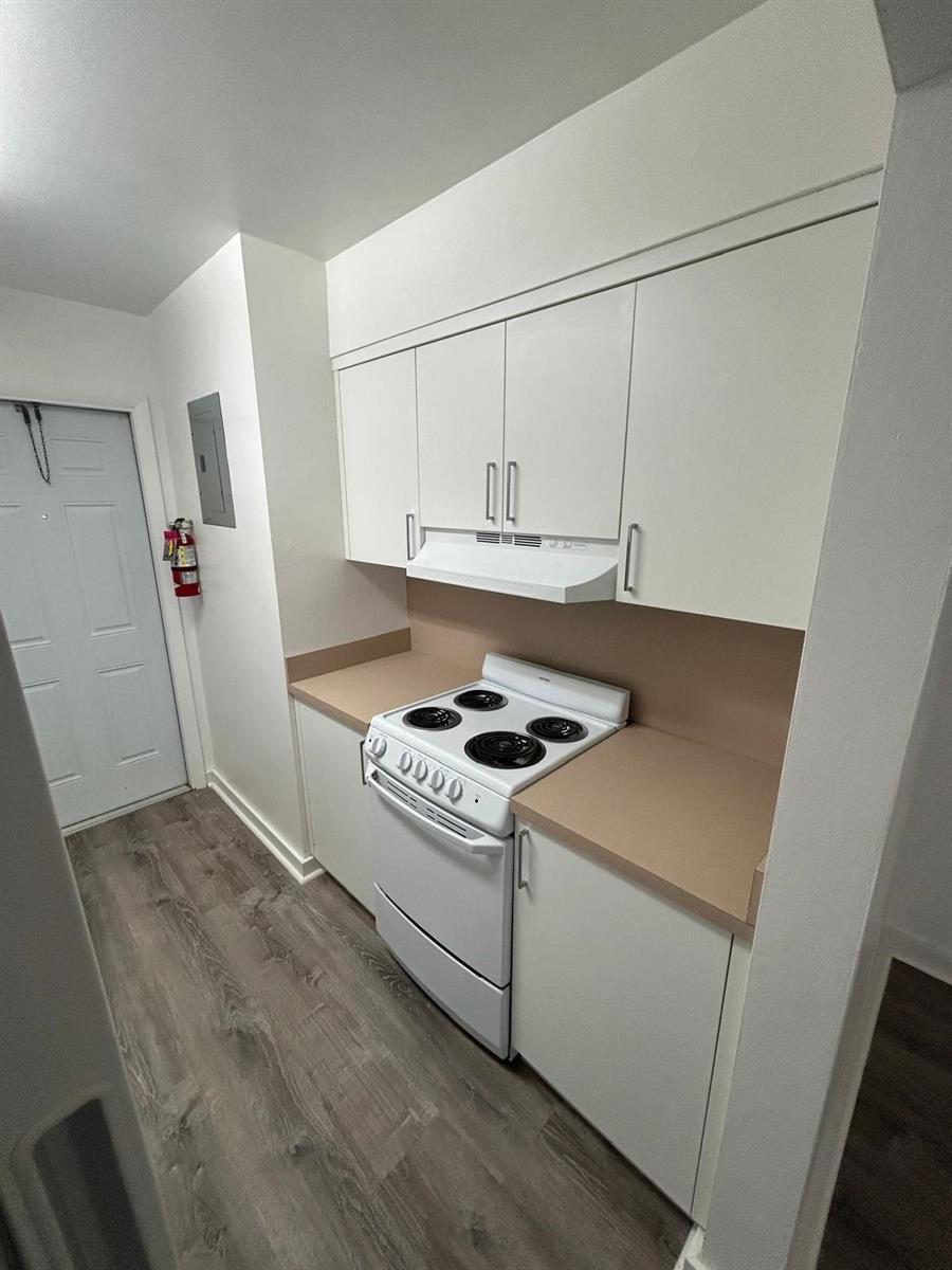 A small kitchen features white cabinets, a white electric stove, and light-colored countertops — 7624 Pembroke Road # D, Miramar FL 33023, MIRAMAR, FL