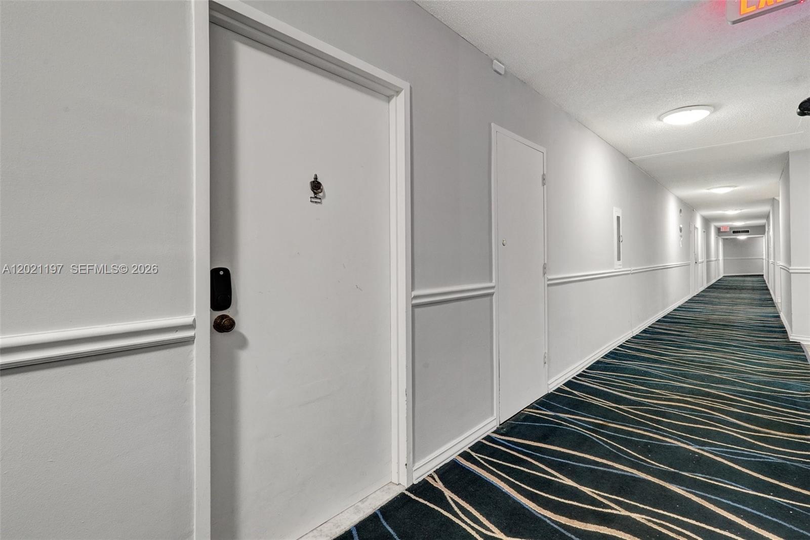 A long, narrow hallway features white walls, a patterned carpet, and several closed doors — 3725 S Ocean Dr # 812, Hollywood FL 33019, HOLLYWOOD, FL