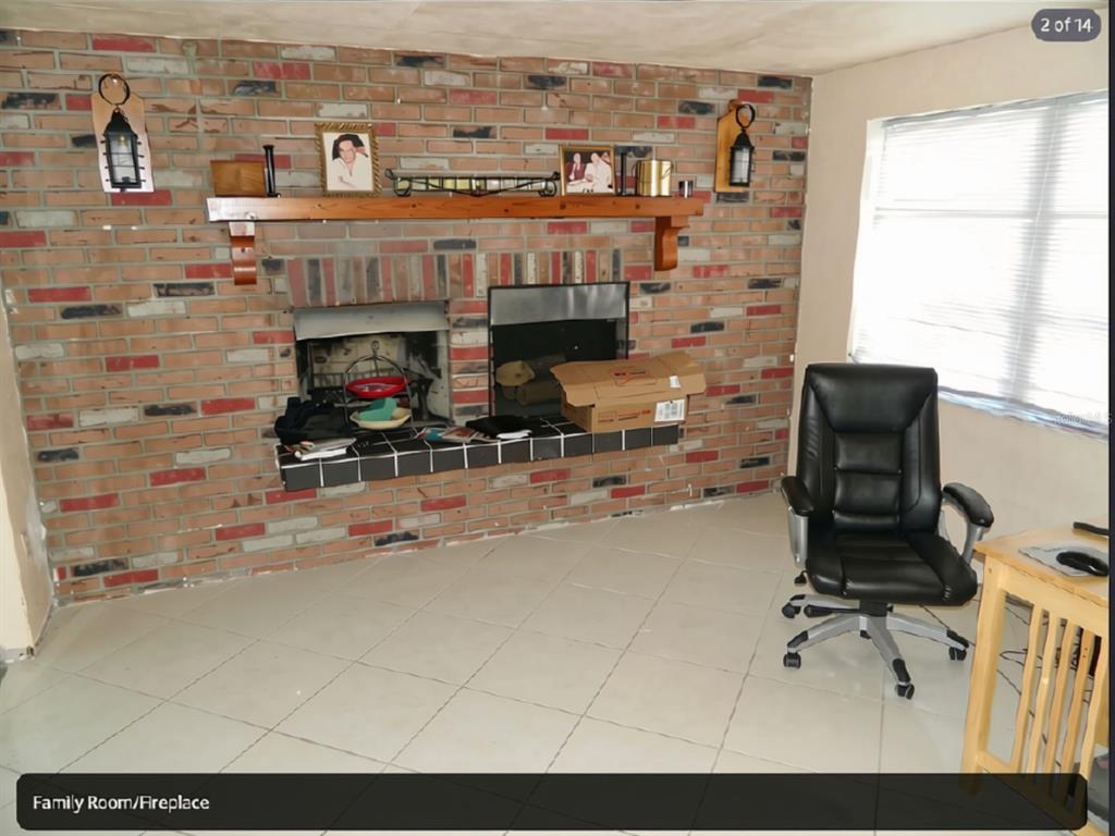 A family room features a large brick fireplace with a wooden mantel and tile flooring — 3442 WILTSHIRE DRIVE, HOLIDAY, FL