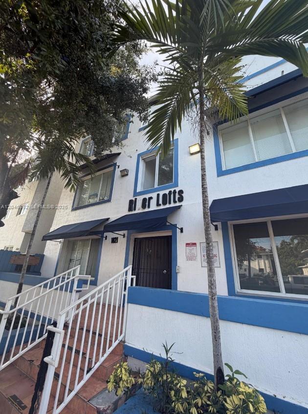 The exterior of a white multi-story apartment building with blue trim and a palm tree — 1021 NW 3rd St # 106, Miami FL 33128, MIAMI, FL
