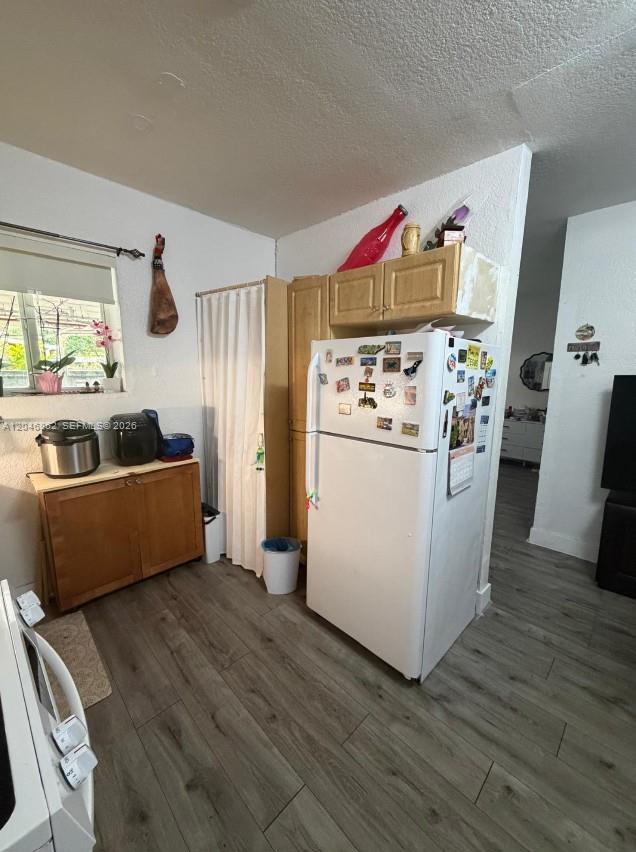 A kitchen features light wood cabinets, a white refrigerator, and gray wood-look flooring — 1021 NW 3rd St # 106, Miami FL 33128, MIAMI, FL