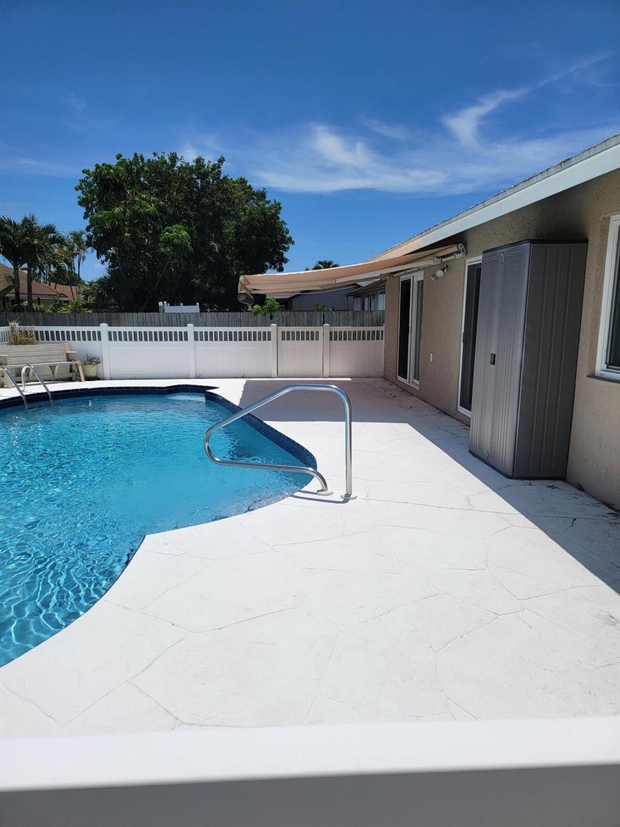 A swimming pool with a white deck, a storage shed, and a retractable patio awning — 27 Vista Del Rio, Boynton Beach FL 33426, BOYNTON BEACH, FL