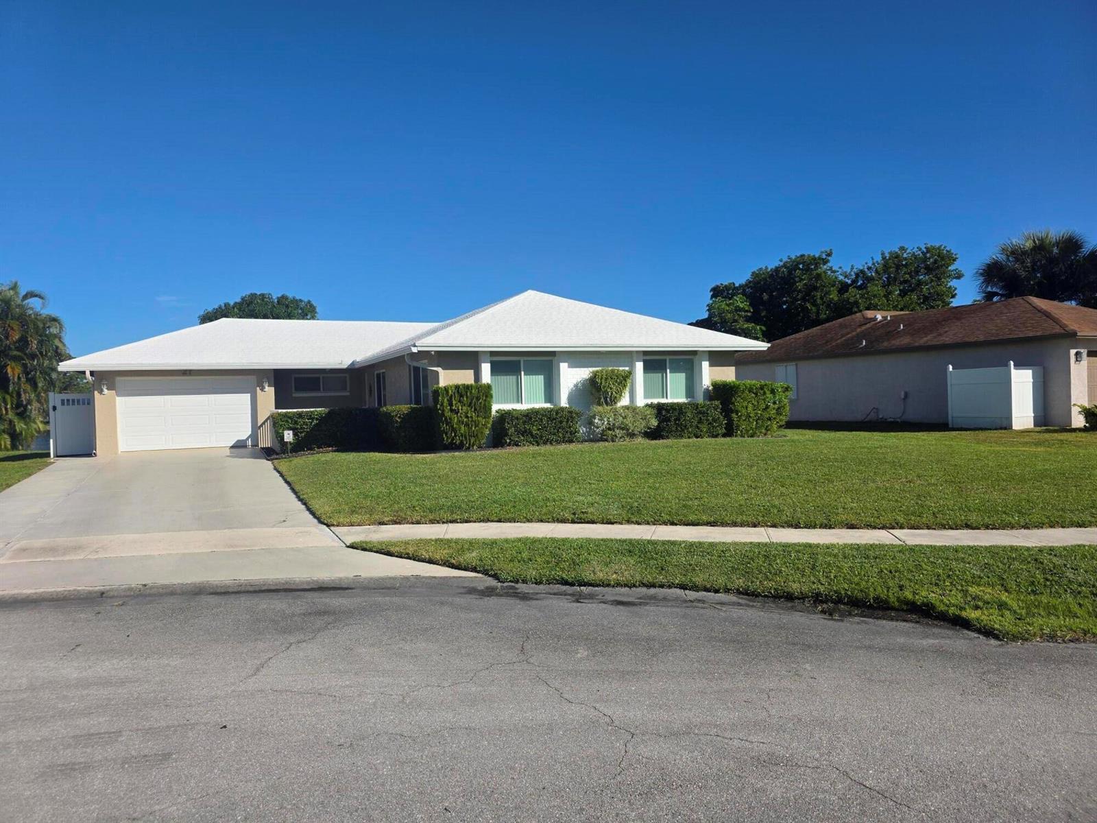 A single-story house with a white roof, beige exterior, and a concrete driveway — 27 Vista Del Rio, Boynton Beach FL 33426, BOYNTON BEACH, FL