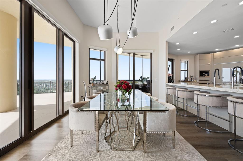 A dining area with a glass table and chairs sits beside a modern kitchen — 14300 RIVA DEL LAGO DRIVE UNIT 2104, FORT MYERS, FL