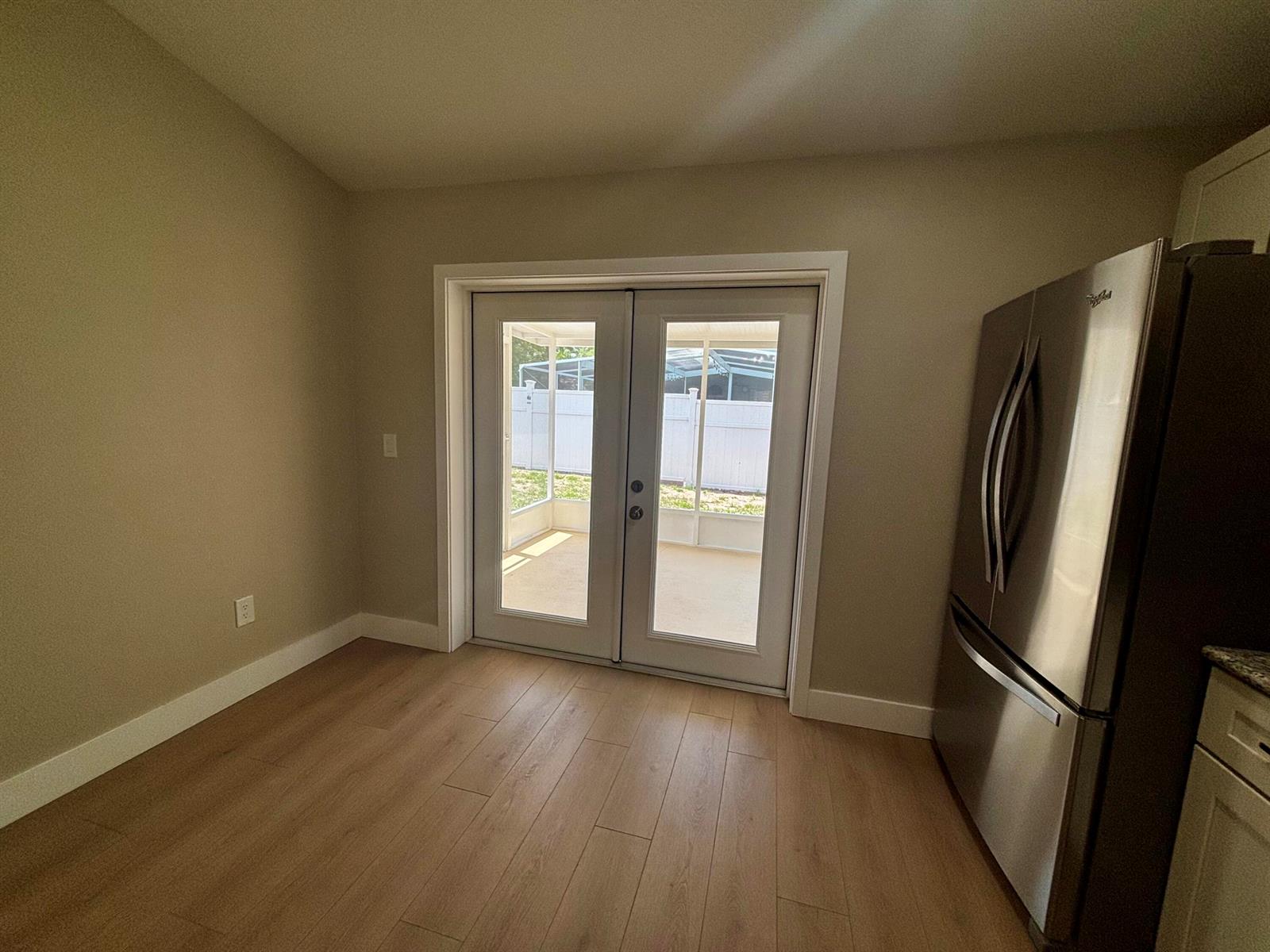 A kitchen dining area features light wood flooring, beige walls, and French doors leading outside — 1001 Harvest Moon Drive, FL 33584, FL