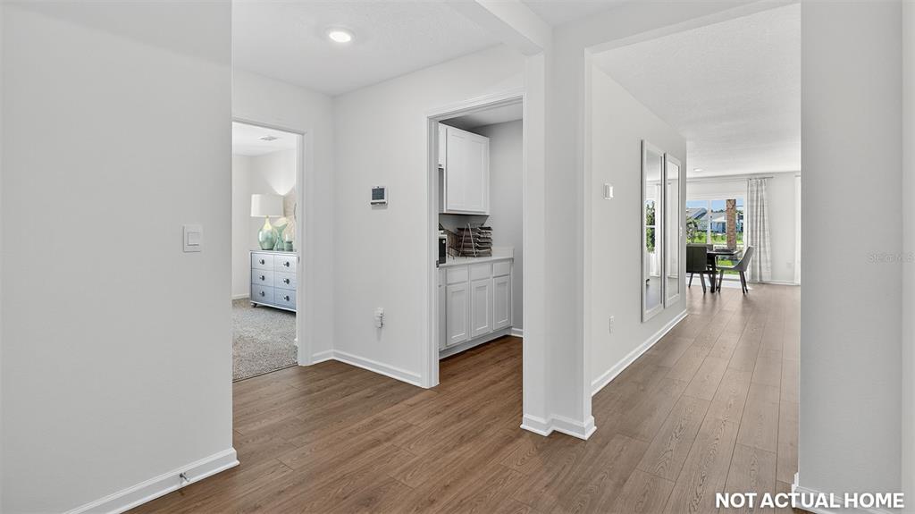 This interior view shows a hallway with wood-look flooring leading to a kitchen and dining area — 71 RYAN DRIVE, PALM COAST, FL