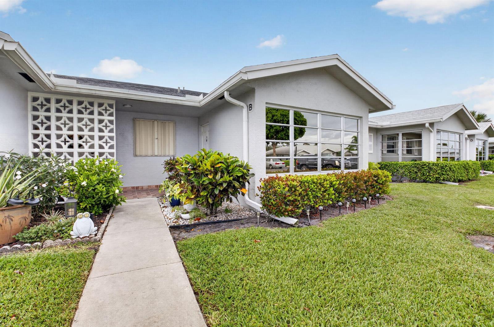 A single-story residential building with a concrete walkway, decorative screen wall, and landscaped lawn — 14579 Canalview Drive # B, Delray Beach FL 33484, DELRAY BEACH, FL