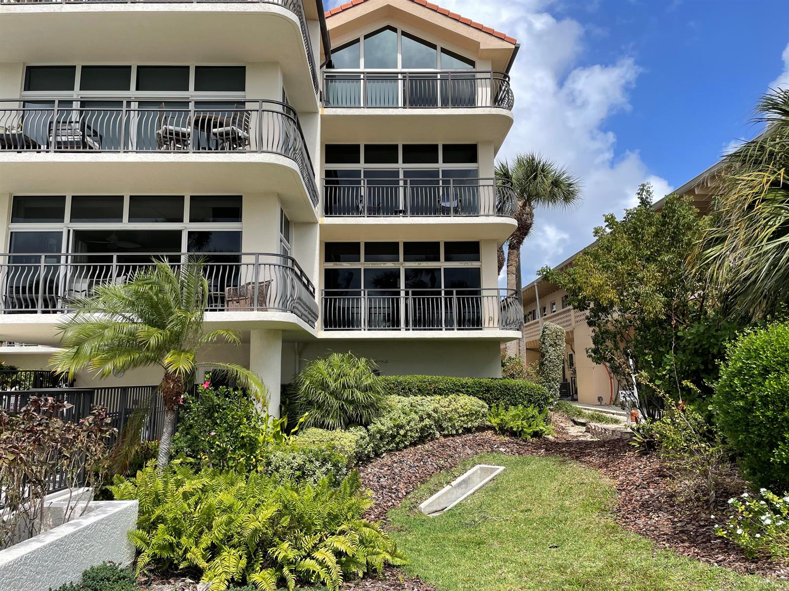 A multi-story building with balconies and large windows overlooks a landscaped garden and lawn — 314 Inlet Way # 201, Palm Beach Shores FL 33404, PALM BEACH SHORES, FL