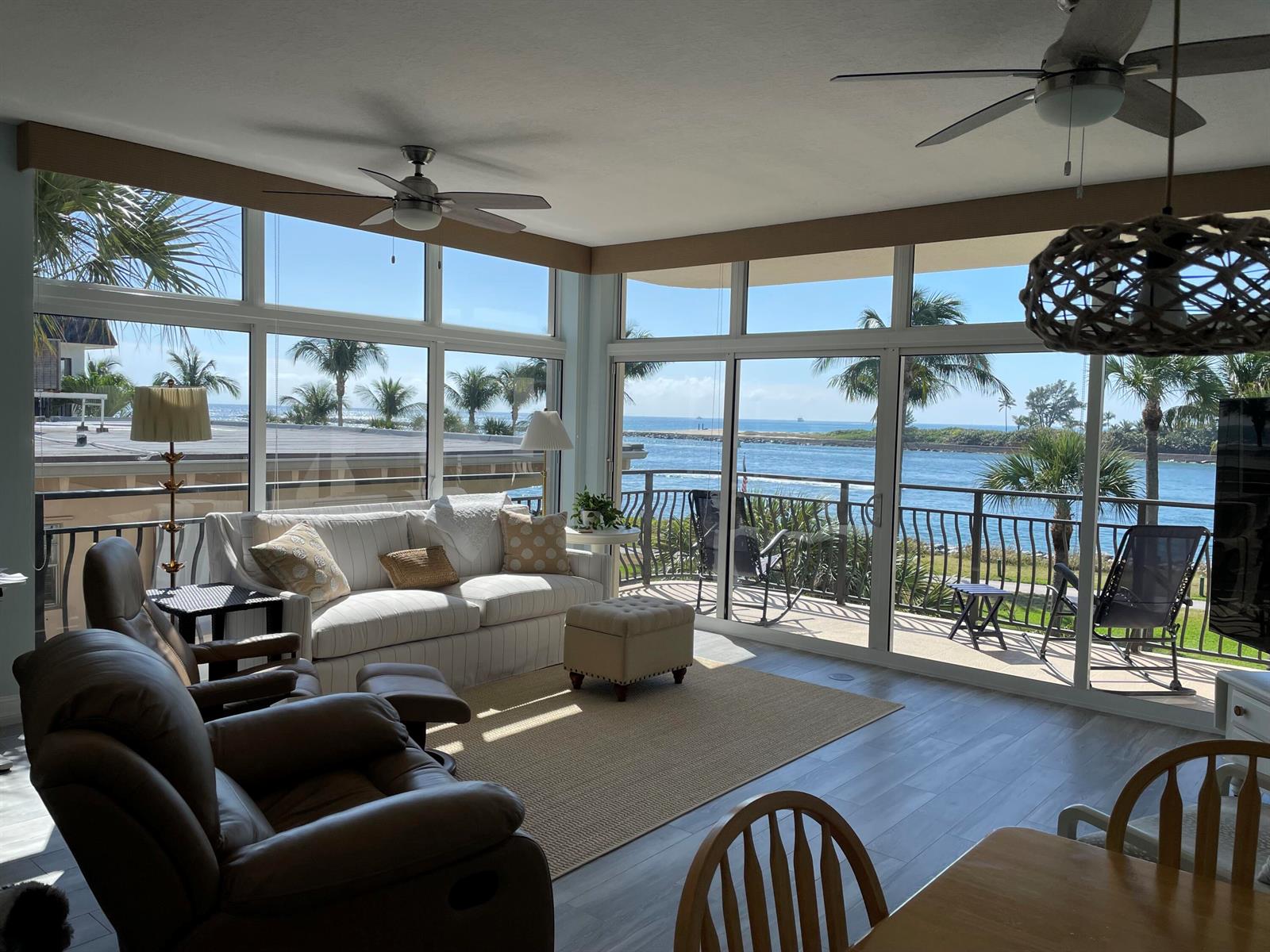 A sunroom with a white sofa, leather recliner, and large windows overlooking a coastal waterway — 314 Inlet Way # 201, Palm Beach Shores FL 33404, PALM BEACH SHORES, FL