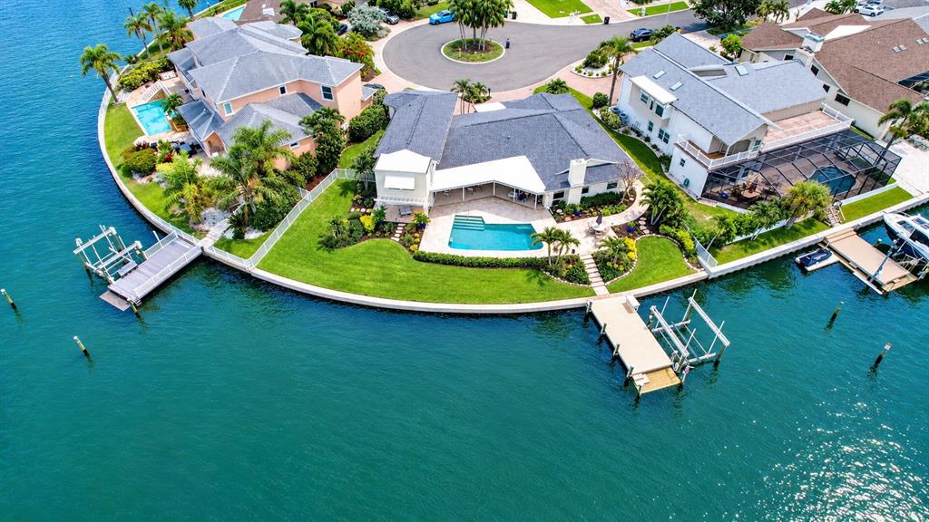 An aerial view shows two waterfront houses with swimming pools, private docks, and manicured lawns — 812 SNUG ISLAND, CLEARWATER BEACH, FL