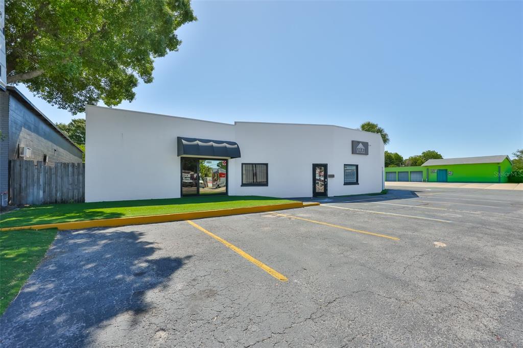 A white commercial building with a black awning and parking lot under a clear sky — 1801 28TH STREET N, ST PETERSBURG, FL