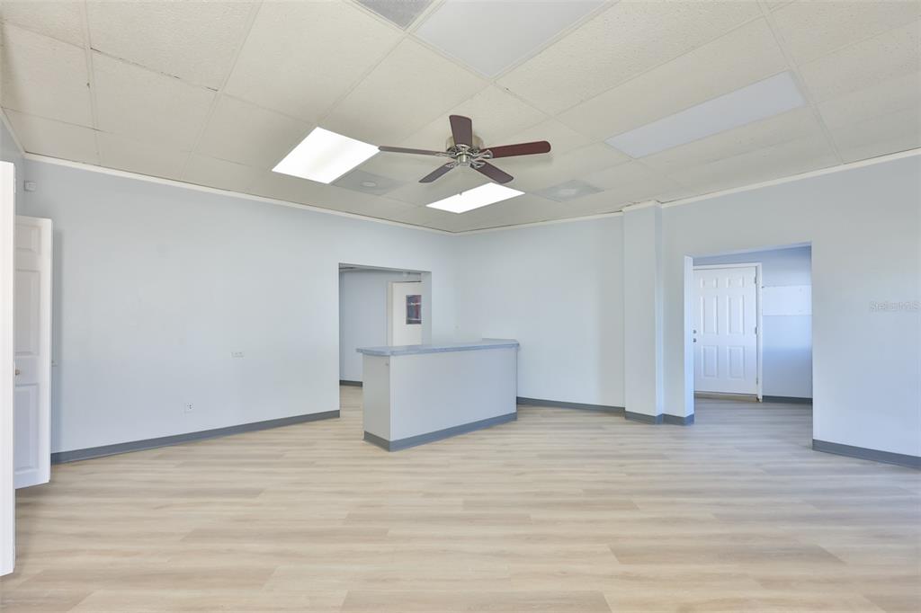 An empty office space features light-colored wood-look flooring, a drop ceiling, and a central counter — 1801 28TH STREET N, ST PETERSBURG, FL