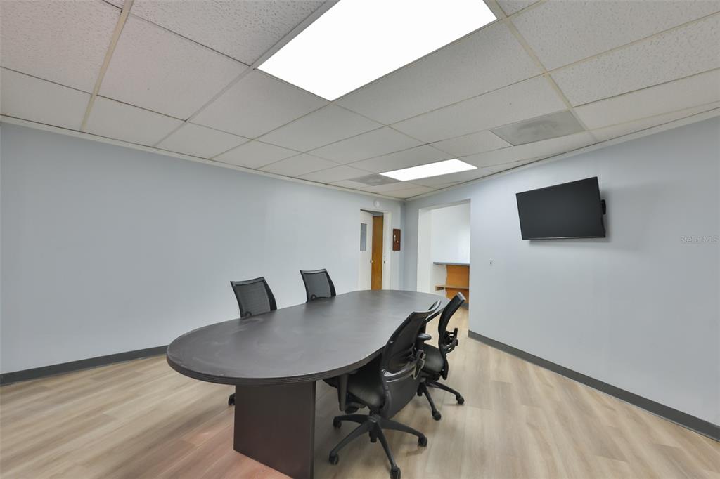 A conference room features a dark oval table, black office chairs, and light wood flooring — 1801 28TH STREET N, ST PETERSBURG, FL