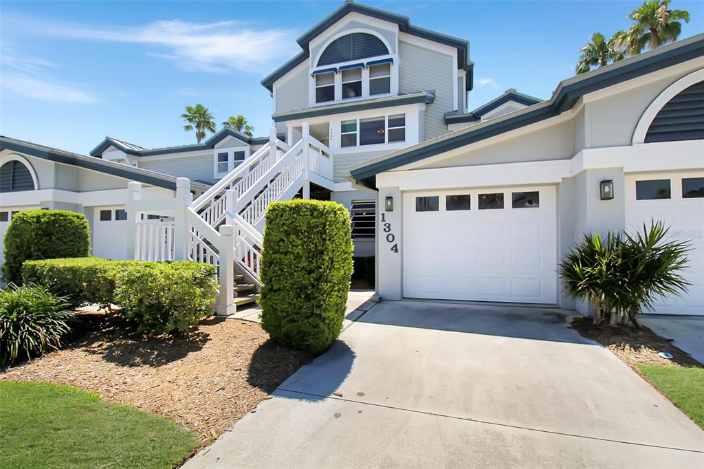 A two-story house features a white garage, a staircase leading to an entrance, and landscaping — 1304 SIESTA BAYSIDE DRIVE UNIT 1304B, SARASOTA, FL