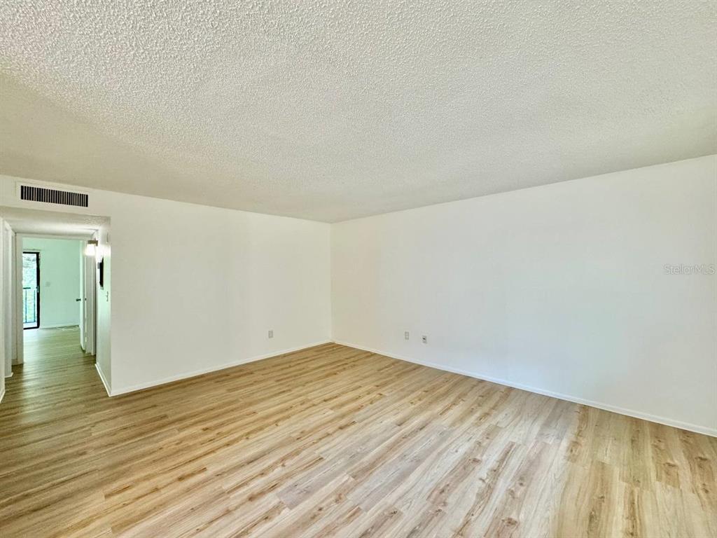 An empty room with light wood-look flooring, white walls, and a textured ceiling — 11703 RAINTREE VILLAGE BOULEVARD UNIT C, TAMPA, FL