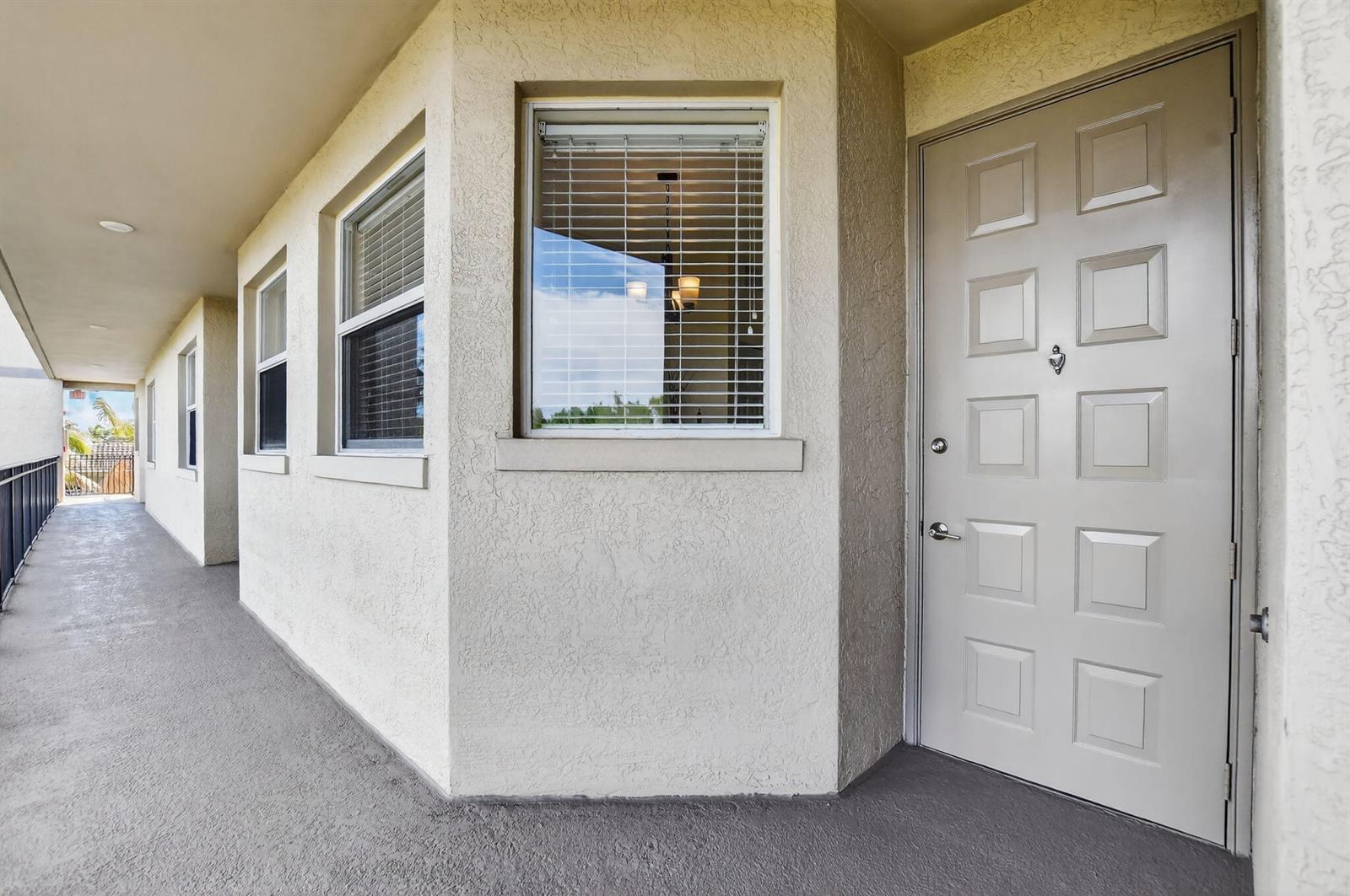 A beige exterior wall with a door and windows along a covered outdoor walkway — 26 Royal Palm Way # 403, Boca Raton FL 33432, BOCA RATON, FL