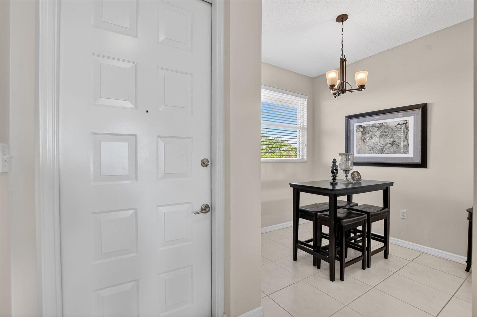A white front door opens into a dining area with a dark table and tile floors — 26 Royal Palm Way # 403, Boca Raton FL 33432, BOCA RATON, FL