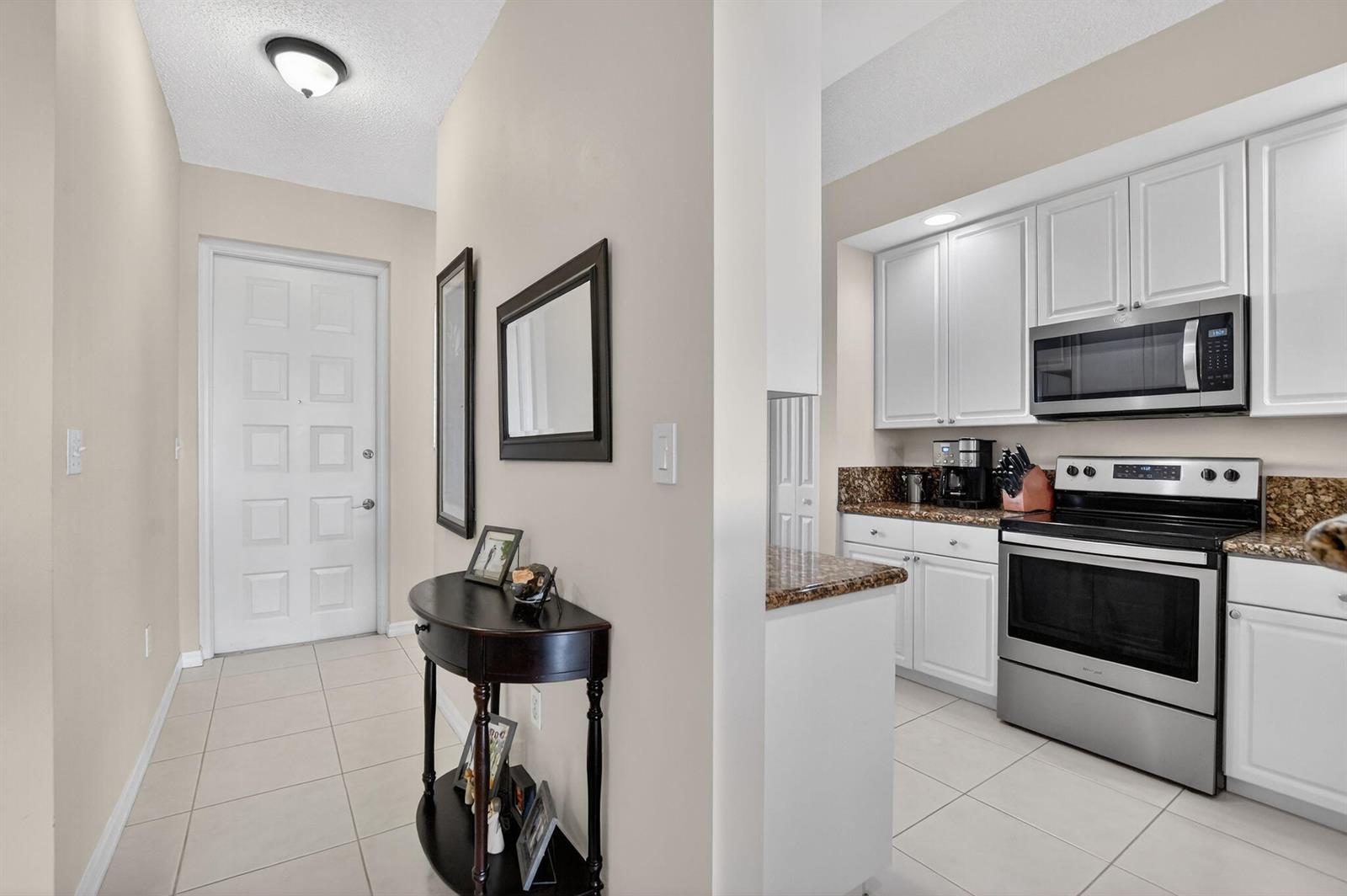 A tiled entryway leads to a kitchen featuring white cabinets and stainless steel appliances — 26 Royal Palm Way # 403, Boca Raton FL 33432, BOCA RATON, FL
