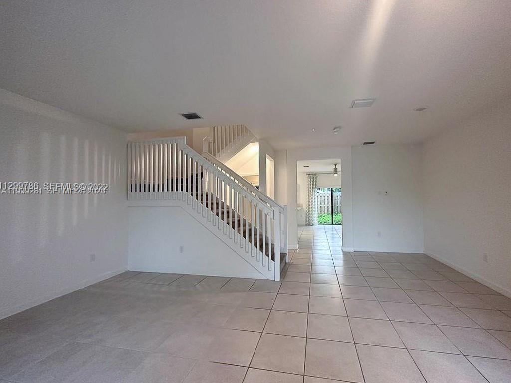 An interior view shows a tiled living area with a white staircase and a doorway — 20800 NE 5th Ct, Miami FL 33179, MIAMI, FL