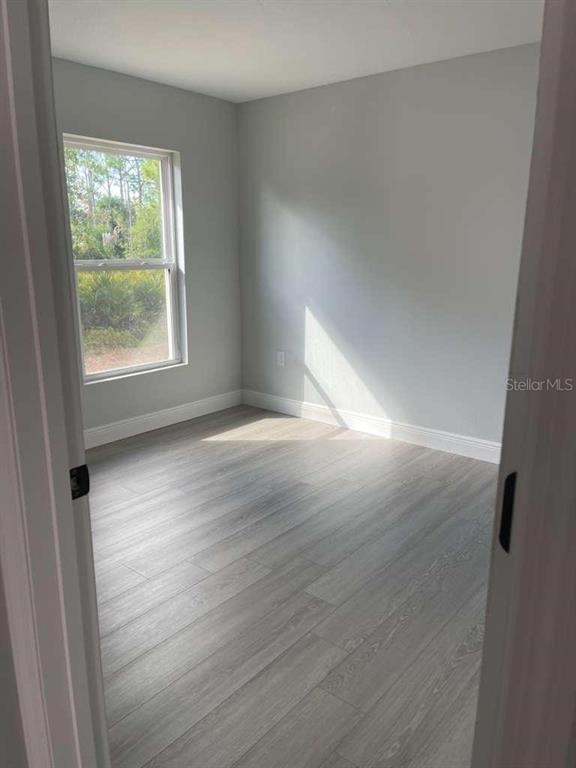An empty bedroom features light gray walls, wood-look flooring, and a single window — 17512 POSTON AVENUE, PORT CHARLOTTE, FL