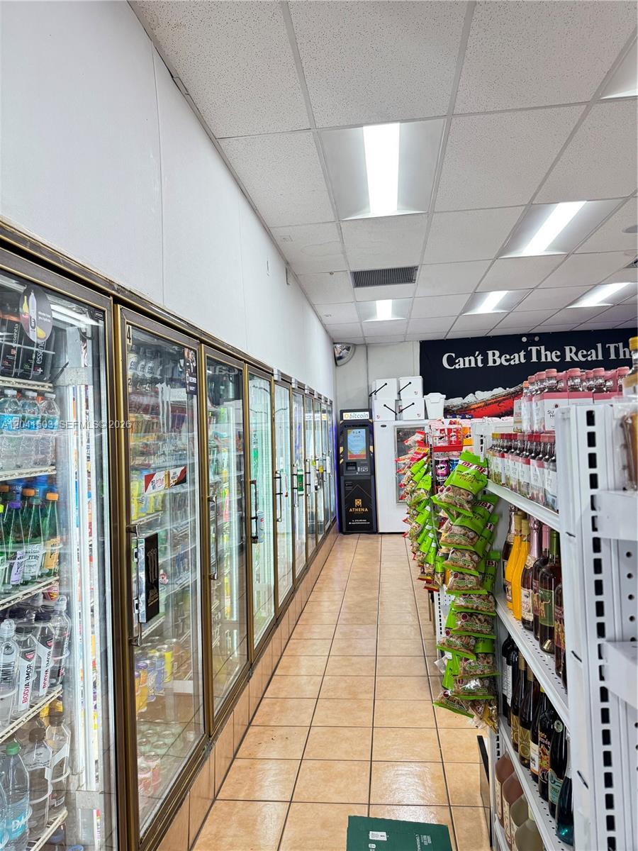 A narrow convenience store aisle features glass-front refrigerators on one side and shelving on the other — 6776 SW 117th Ave, Miami FL 33183, MIAMI, FL